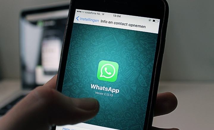 Imagem mostra smartphone com aplicativo do WhatsApp e ao fundo da foto um notebook ligado