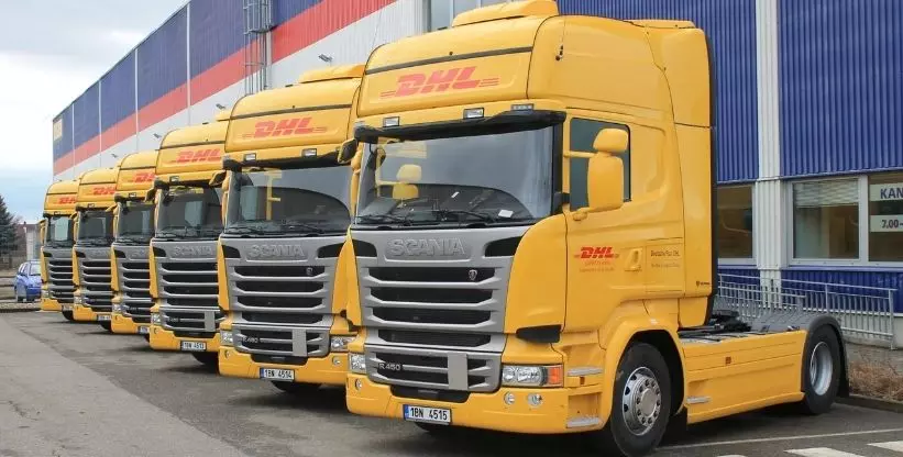 A foto mostra uma parte da frota de caminhões e carretas da empresa DHL